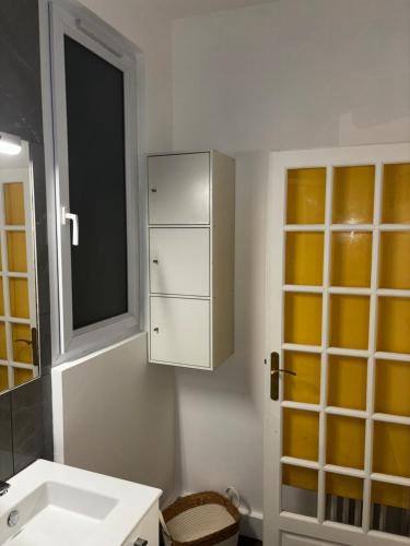 La salle de bains blanche est pourvue d'un lavabo et d'une armoire. dans l'établissement L'étoile de duhesme, à Paris