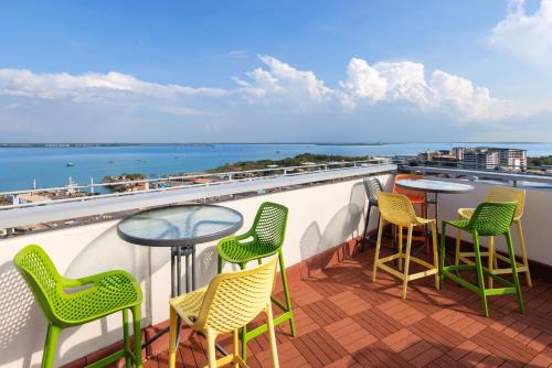a balcony with chairs and tables and a view of the water at Ramada Suites by Wyndham Zen Quarter Darwin in Darwin