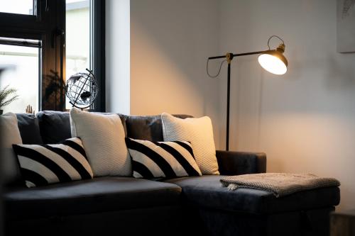 a couch with black and white pillows and a lamp at Modern 2-Bed Apartment with Balcony, Close To Oxford City Centre With Free Parking in Oxford