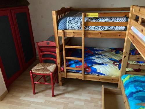 a bedroom with two bunk beds and a red chair at Lou Raspaillou in Issigeac
