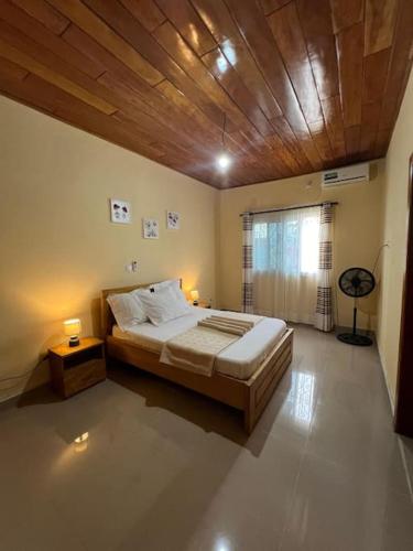 een slaapkamer met een groot bed en een houten plafond bij Villa Dave Kribi in Kribi