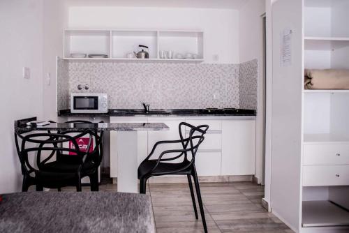 a kitchen with two chairs and a table with a microwave at Apart Valeria cerca del Mar in Valeria del Mar