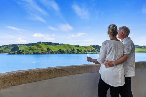 a man and a woman standing on a wall overlooking a lake at The Silos Apartments in Raglan