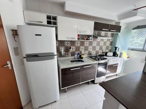 a kitchen with a white refrigerator and a stove at Cantinho dos Sonhos in Mangaratiba