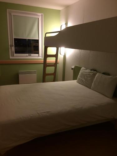 a bedroom with a bed and a ladder and a window at Ibis budget Verdun in Verdun