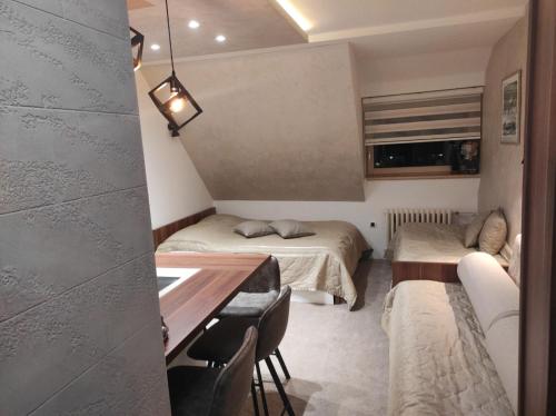 a small room with two beds and a table at Apartmani Iva Kop Konaci in Kopaonik