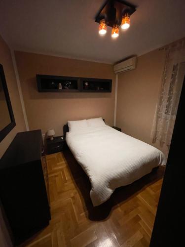 a bedroom with a bed with white sheets and a table at AP Apartment in Kotor