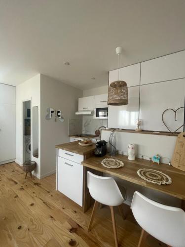 une cuisine avec une table en bois et des armoires blanches dans l'établissement Rayon de soleil, à Palavas-les-Flots