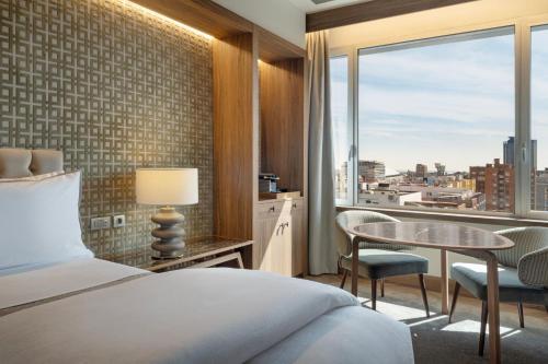 a bedroom with a bed and a table and a window at The Westin Madrid Cuzco in Madrid
