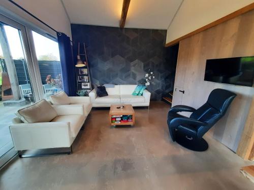 a living room with a white couch and a chair at Vakantievilla 10 km van strand honden welkom omheinde tuin sauna buitenbad in Dirkshorn