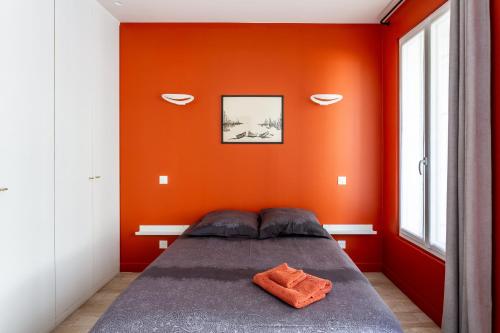 - une chambre avec un mur orange et un lit dans l'établissement Stade de France & 15min de Montmartre, à Saint-Denis