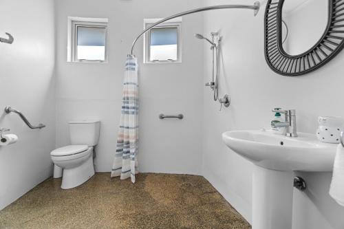 a bathroom with a toilet and a sink and a mirror at The Silos Apartments in Raglan