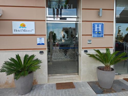 a store front with two palm trees in front of it at Hotel Miraya Beach in Torre del Mar
