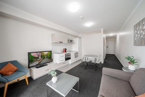 a living room with a couch and a tv and a table at Lakeside 1-Bed with AC, Parking & Balcony in Tuggeranong
