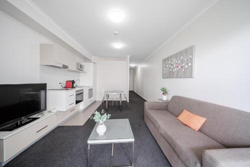 a living room with a couch and a tv at Lakeside 1-Bed with AC, Parking & Balcony in Tuggeranong