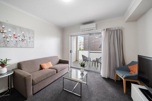 a living room with a couch and a tv at Lakeside 1-Bed with AC, Parking & Balcony in Tuggeranong