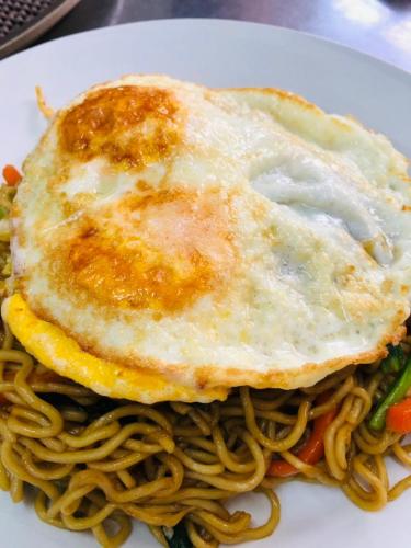 a plate of noodles with a fried egg on top at Palm Beach Hotel Dili in Dili