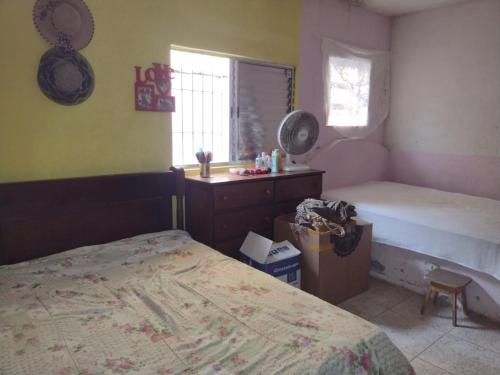 a bedroom with a bed and a dresser and a window at Casa da Vovó in Praia Grande