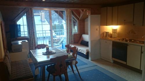 kuchnia i jadalnia ze stołem oraz pokój z oknem w obiekcie ApartBabsi w mieście Kappl