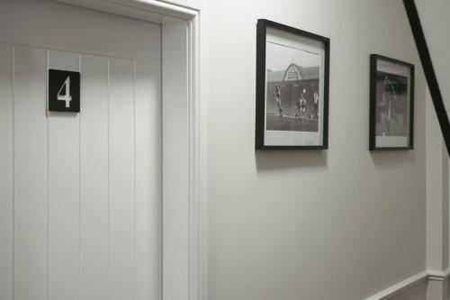 a hallway with two pictures on a wall and a door at The Boot Rooms Anfield in Liverpool