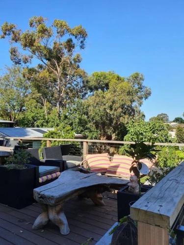 a wooden deck with a bench and a table at Family beach house among the gum trees in Ocean Grove