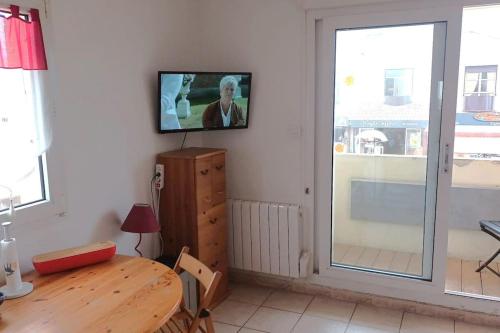 un salon avec une table et une télévision au mur dans l'établissement Appartement à 20 m de la plage, à Lacanau