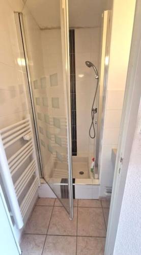 une douche avec une porte vitrée dans une salle de bain dans l'établissement Appartement à 20 m de la plage, à Lacanau