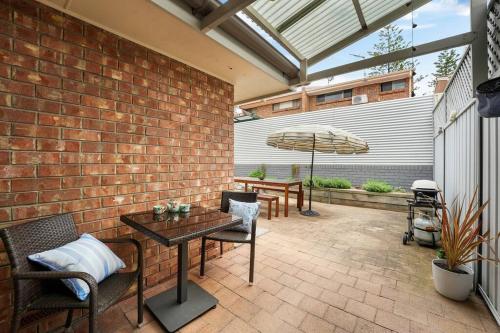 a patio with a table and chairs and an umbrella at Sapphire by the Sea - Beach Family Modern in Grange