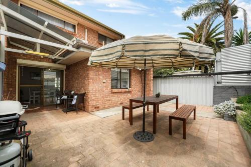 a patio with an umbrella and a table and benches at Sapphire by the Sea - Beach Family Modern in Grange