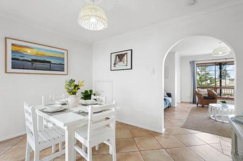 a white dining room with a white table and chairs at Sapphire by the Sea - Beach Family Modern in Grange
