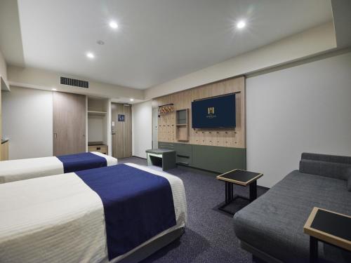 a hotel room with two beds and a flat screen tv at hotel MONday Akihabara Asakusabashi in Tokyo