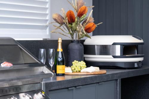 a counter with a bottle of wine and a microwave at Serendipity, Kangaroo Valley in Barrengarry