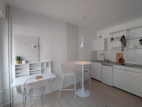 une cuisine avec des armoires blanches et une table et des chaises dans l'établissement Le pur chic - Strasbourg centre, à Strasbourg