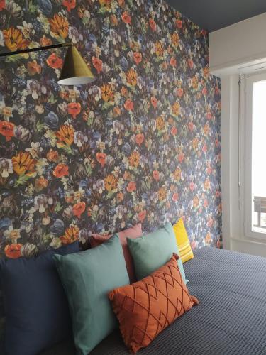 - une chambre avec une fresque murale florale et un canapé dans l'établissement Le pur chic - Strasbourg centre, à Strasbourg
