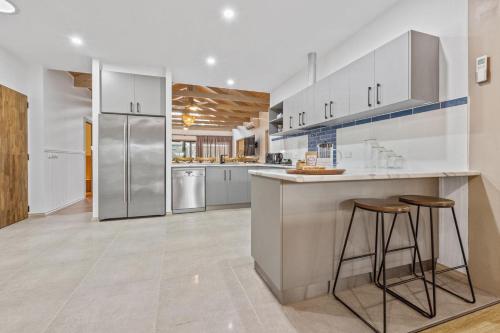 a large kitchen with white cabinets and bar stools at Island House in Raymond Island