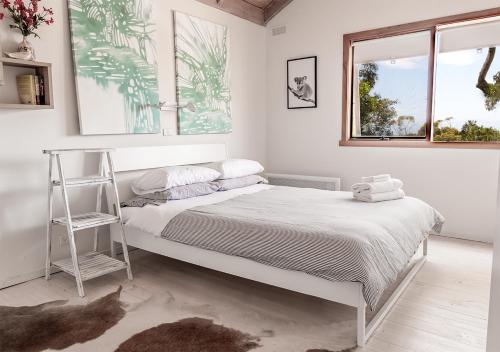 ローンにあるWatershack - Expansive ocean views, close to townの白いベッドルーム(ベッド1台、窓2つ付)