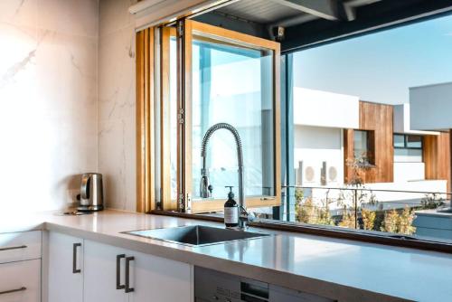a kitchen with a sink and a large window at Blue Pearl Retreat - Opp Beach, Spa, Sunsets and Pool in Mornington