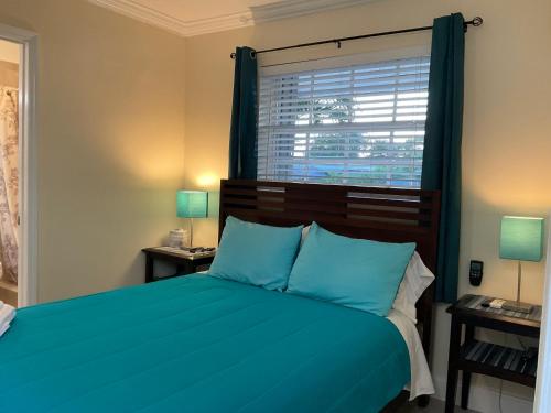a bedroom with a bed with blue pillows and a window at Cozy Guest Room in Pompano Beach