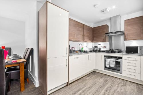 a kitchen with white cabinets and a wooden table at Luxury City Centre 3Bedroom 5Beds Apartment with Allocated Parking in Birmingham