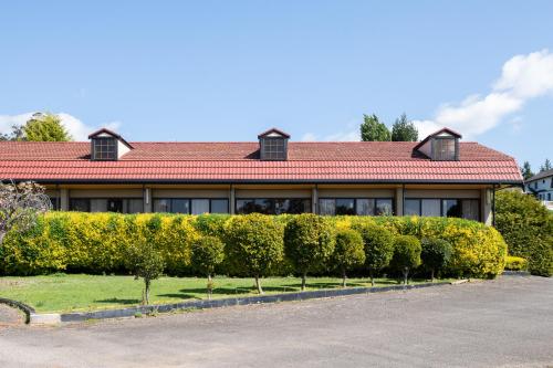 a building with a row of bushes in front of it at Village Family Motor Inn in Launceston