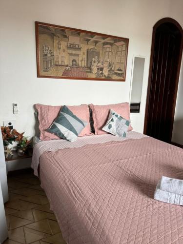 a bedroom with a bed with pink sheets and pillows at Pousada Casa de Buzios in Búzios