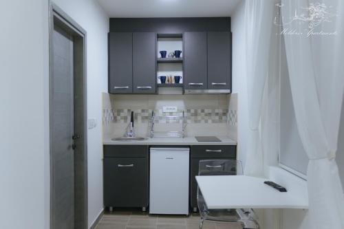 a kitchen with black cabinets and a white sink at Molders Apartments in Belgrade