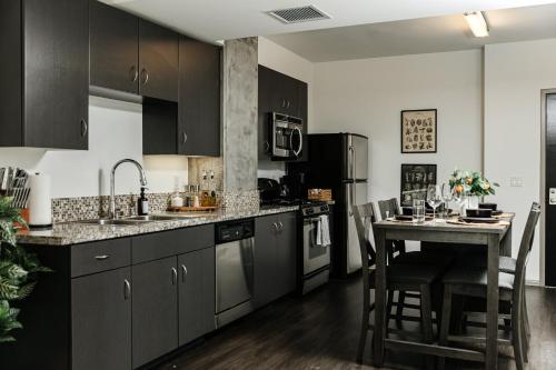 a kitchen with black cabinets and a table with a counter at Oasis in heart of Hollywood in Los Angeles