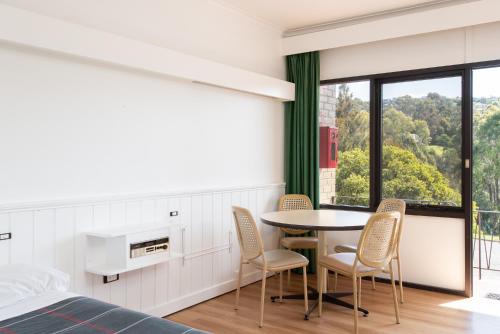 a bedroom with a bed and a table and chairs at Village Family Motor Inn in Launceston