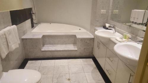 a bathroom with a tub and a sink and a toilet at Melbourne CBD Central Apartment Hotel Official in Melbourne
