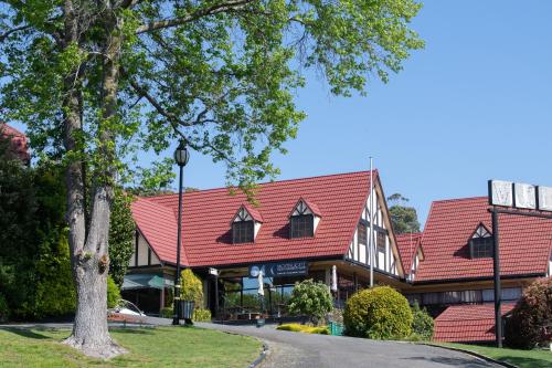 a building with a red roof and a tree at Village Family Motor Inn in Launceston