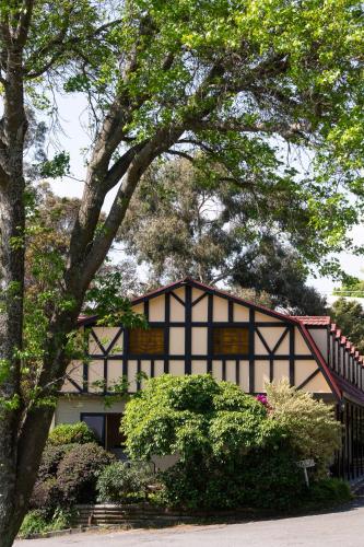 a black and white house with a tree at Village Family Motor Inn in Launceston