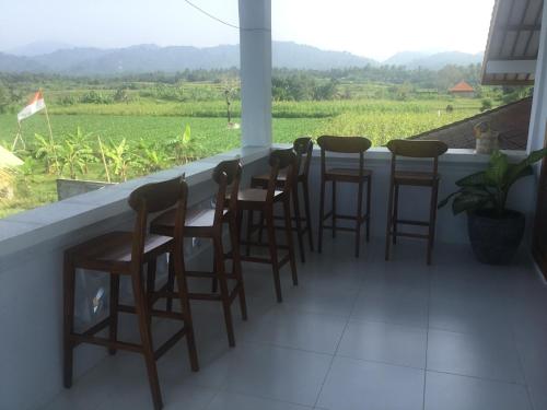 a bar with chairs and a view of a field at Geyu House in Jembrana