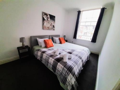a bedroom with a bed with orange pillows and a window at Large 2 beds flat- 3min walk from centre in Reading