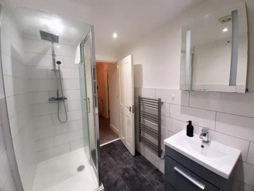 a bathroom with a shower and a sink and a mirror at Large 2 beds flat- 3min walk from centre in Reading
